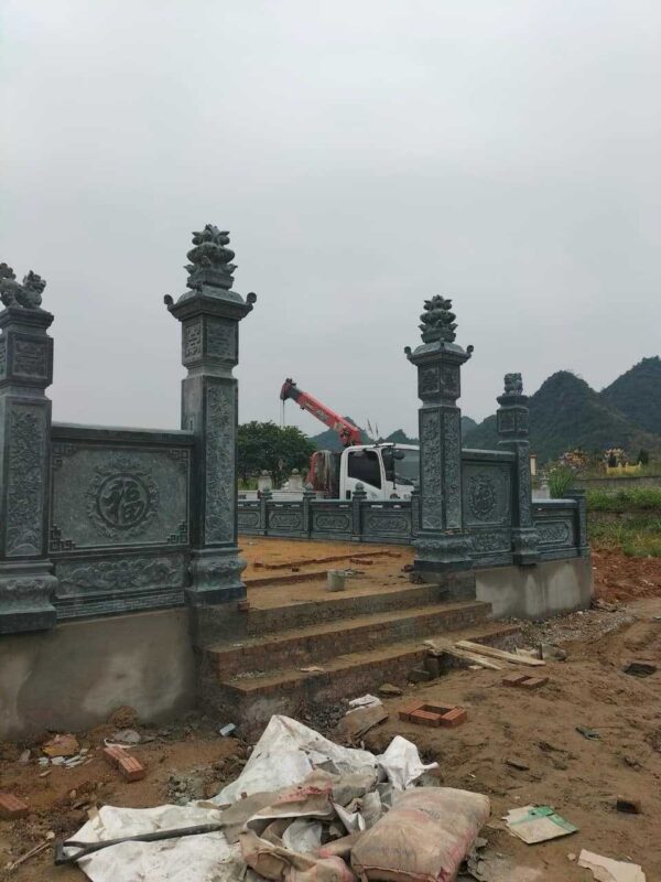 Khu lăng đá xanh đang thi công, trụ cổng đá và xe cẩu phía sau