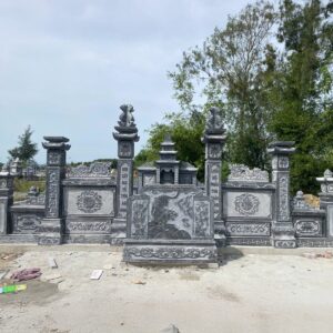 Bình phong cuốn thư đá xanh chạm hoa văn giữa hai trụ cổng khu lăng