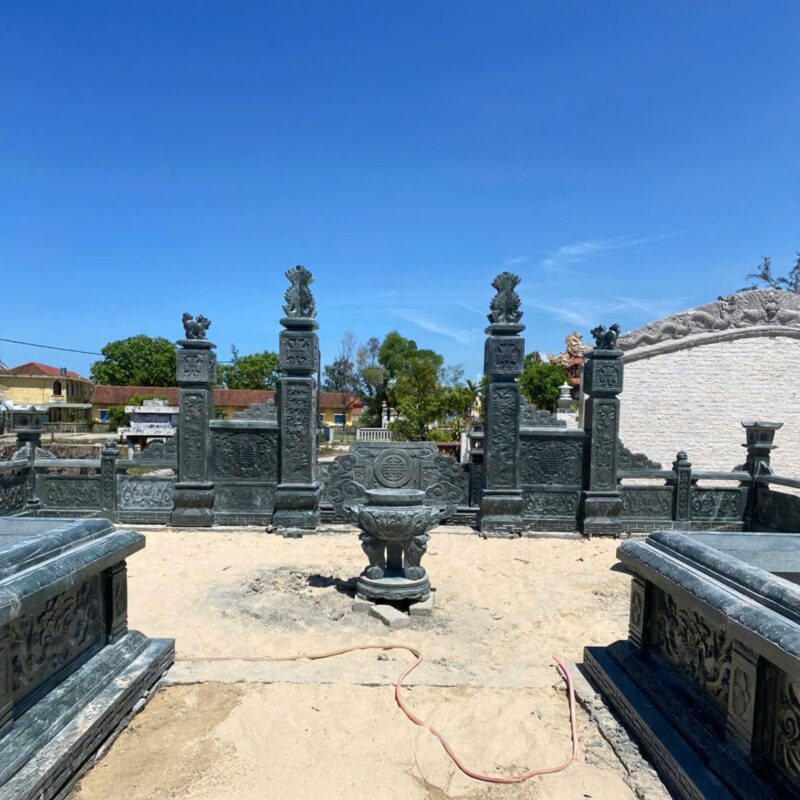 Cổng trụ chạm nghê và mộ đá xanh đen tông đậm trong khu lăng dòng họ