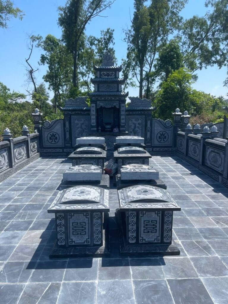 Khu lăng gia đình đá xanh đen có lan can, lăng thờ ba mái và bốn mộ cải táng giữa sân