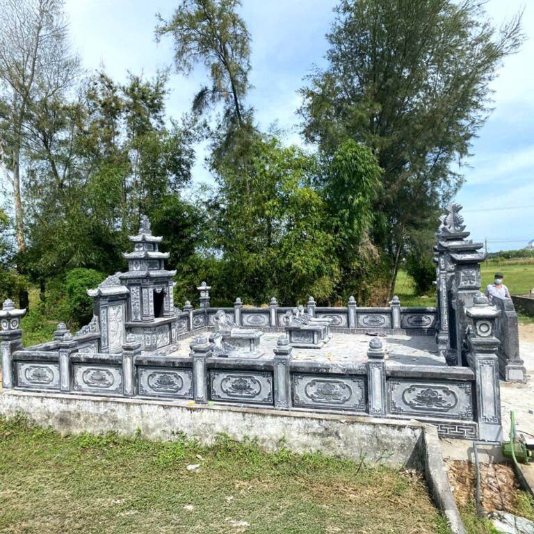 Khu lăng mộ đá xanh có lan can bao quanh và lăng thờ nhỏ giữa vườn cây