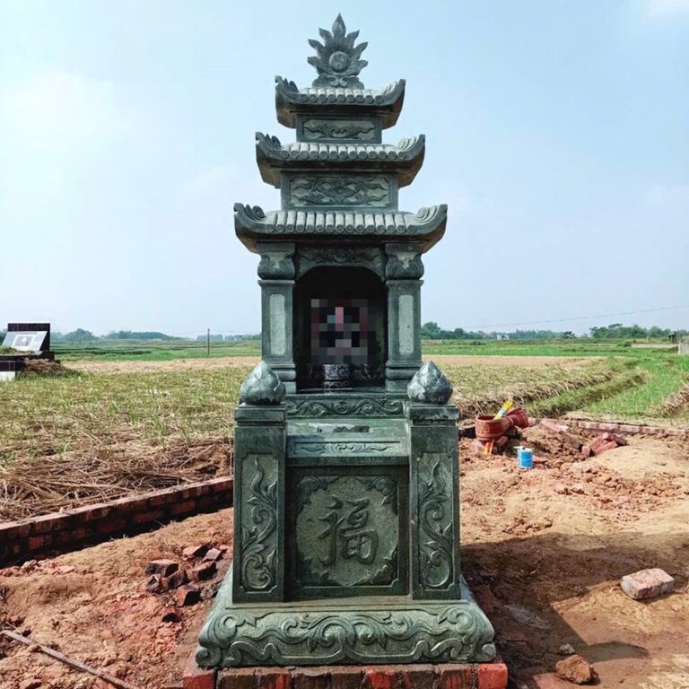 Mộ ba mái đá xanh rêu, thân mộ chạm chữ Phúc, đặt giữa cánh đồng