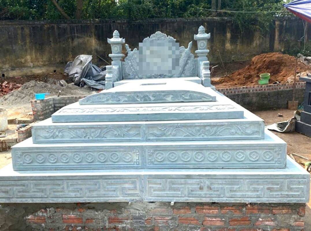 Mộ đá xanh ghi sáng nhiều cấp viền hoa văn chữ triện đặt trên móng xây gạch cao hơn mặt đất
